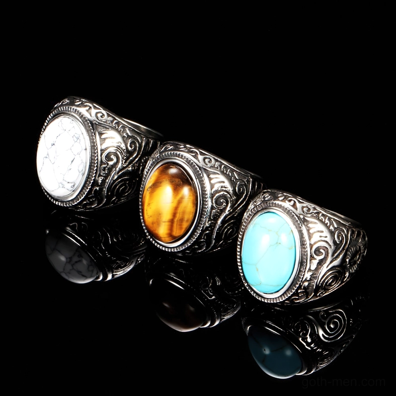 Three vintage gothic stainless steel rings with cracked stone inlays, top oblique view on black reflective background with reflection