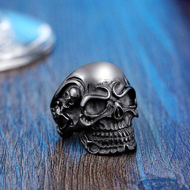 Aged black triple skull gothic ring with side skull emboss details - three-quarter front view