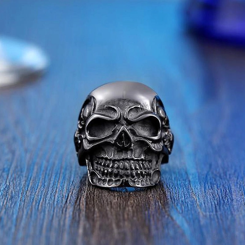 Black matte triple skull gothic biker ring - flat front view on wooden surface
