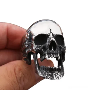 Vampire skull ring worn on human finger, front side view displaying vintage silver-toned finish and polished crown detail against white background
