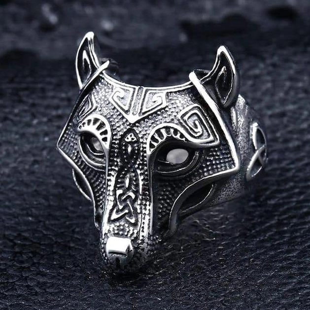 Viking wolf mask ring with geometric engraved patterns, antique silver, oblique front angle on dark leather background