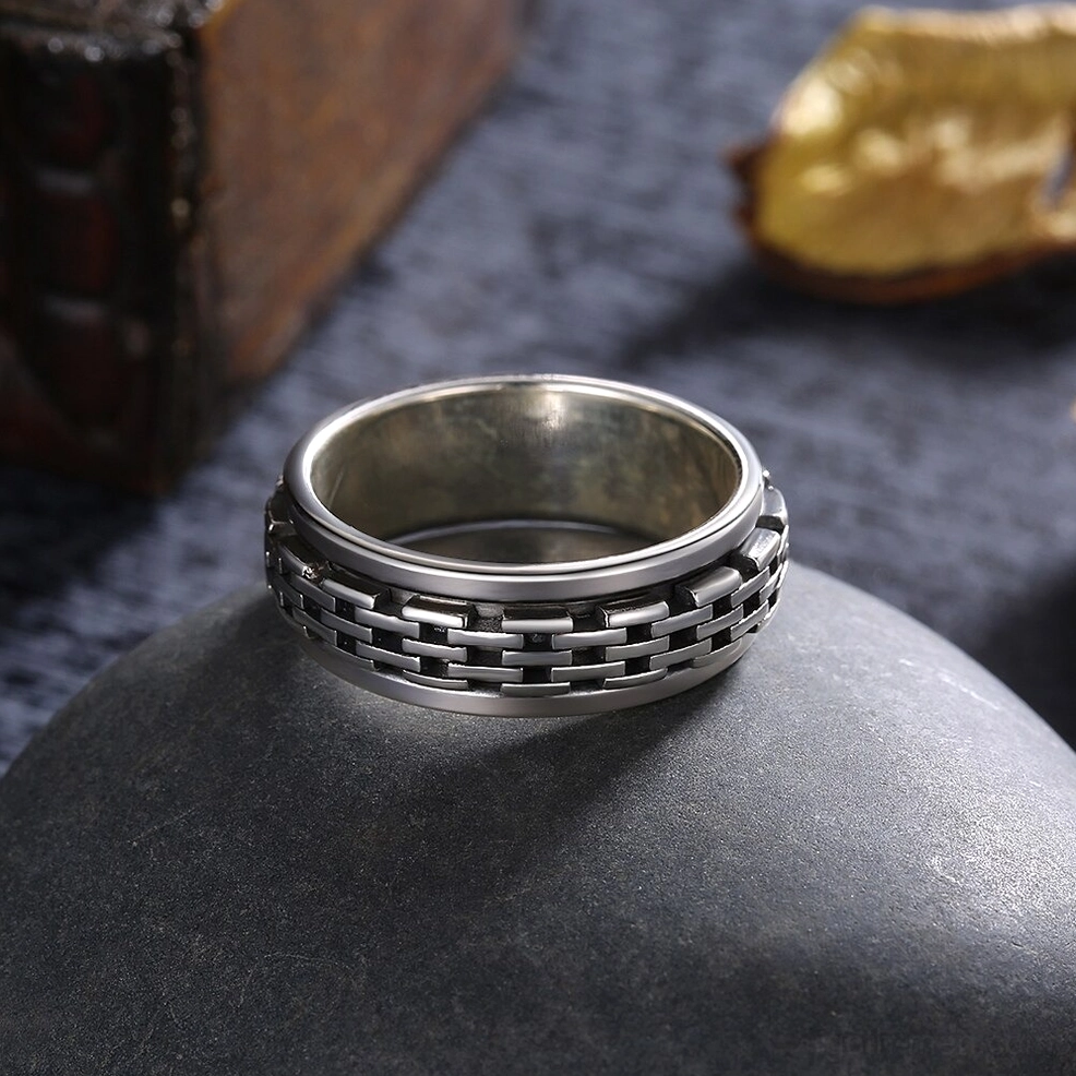 Front overhead view of gothic chain link spinner ring with aged silver tone on vintage stone background