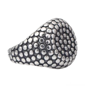 Dark matte stainless steel gothic ring with dense raised dot pattern texture captured from eye-level side perspective