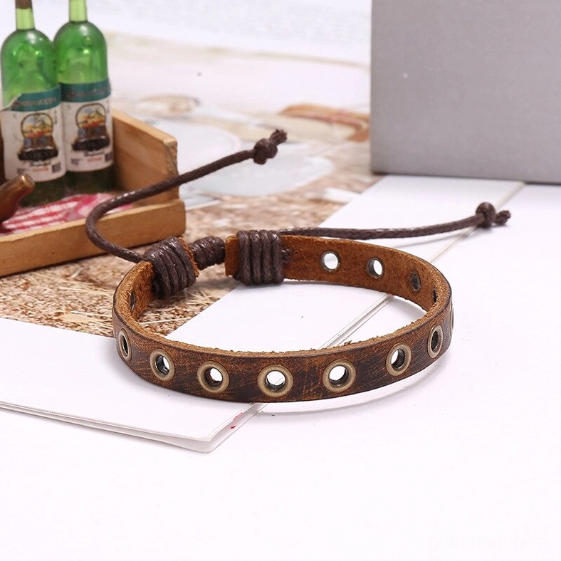 Angled flat lay of vintage brown leather bracelet featuring large metal grommets and distressed tone