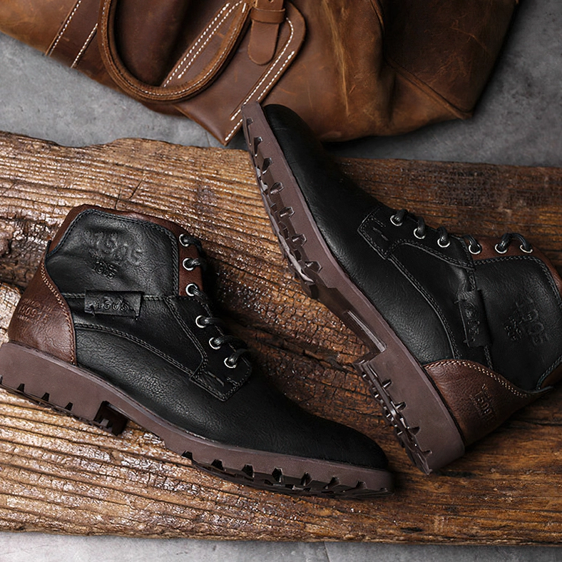 Vintage black and brown leather gothic work boots on wooden board, flat lay styling