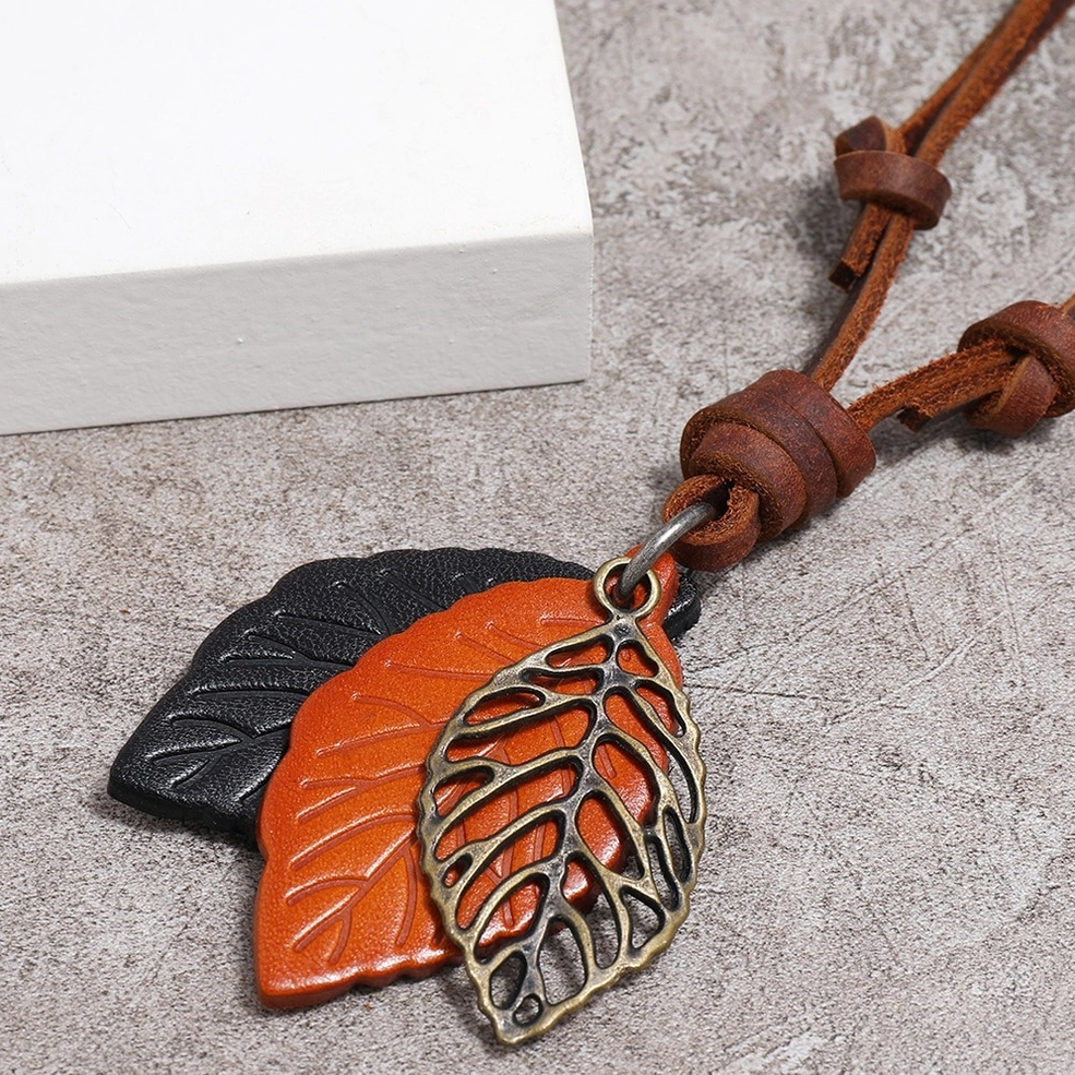 Burgundy and black layered leather leaf pendant with hollow bronze alloy decoration on vintage gothic necklace - flat lay detail