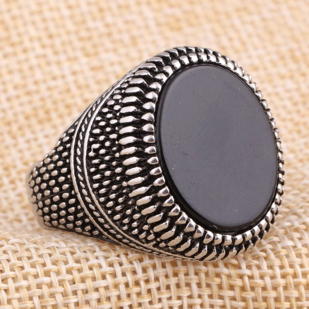 Vintage gothic signet ring oblique side view dotted striped embossed band linen background