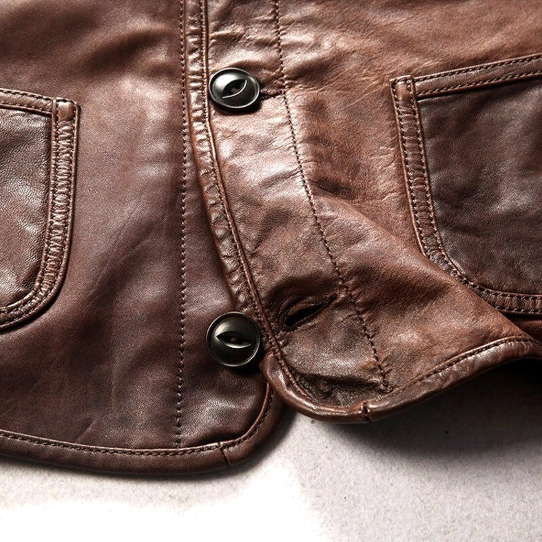 Extreme close-up texture detail of round metal buttons and aged genuine leather surface of gothic biker waistcoat