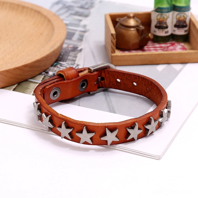 Camel and brown leather gothic bracelets with silver star studs displayed on vintage furniture and classic interior styling