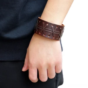 Wide leather gothic cuff bracelet worn on wrist, showcasing cross-stitch detail and snap closure in casual daily outfit setting