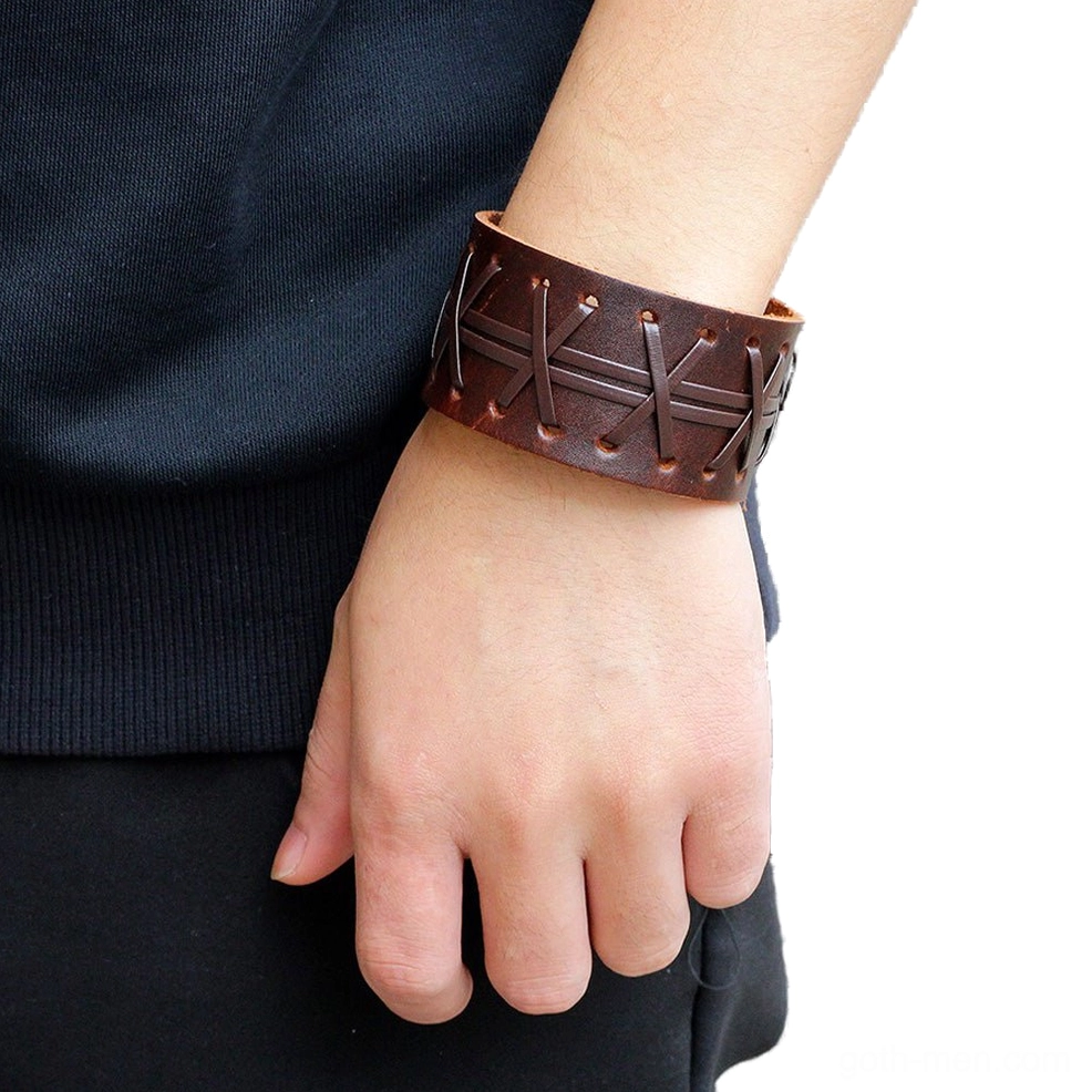 Wide leather gothic cuff bracelet worn on wrist, showcasing cross-stitch detail and snap closure in casual daily outfit setting