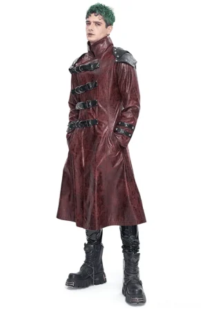 Wine red studded gothic trench coat with multi-buckle harness front three-quarter view on male model with green hair