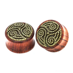Wine red wooden ear gauge with embossed triskele Celtic pattern - front view showing natural wood grain texture and metal triskele accent
