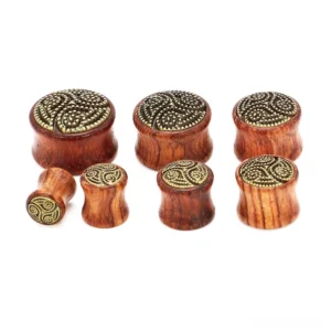 Wooden flesh tunnel gauge in wine red with Celtic triskele design - side profile view displaying depth, wood grain detail, and carved triskele pattern