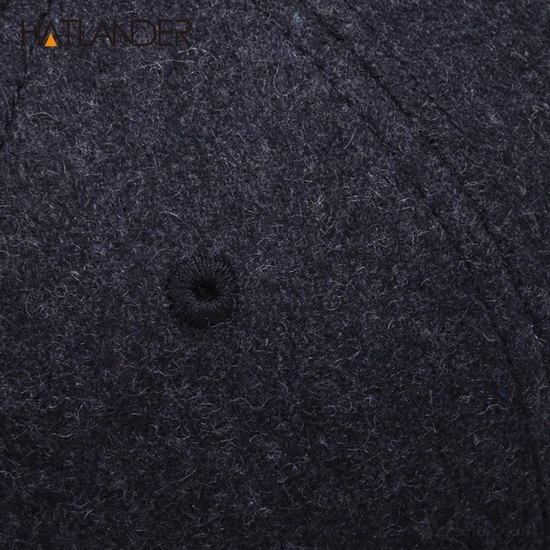 Dark grey wool fabric macro close-up of gothic snapback cap, showing melange texture, ventilation eyelet, and weave quality
