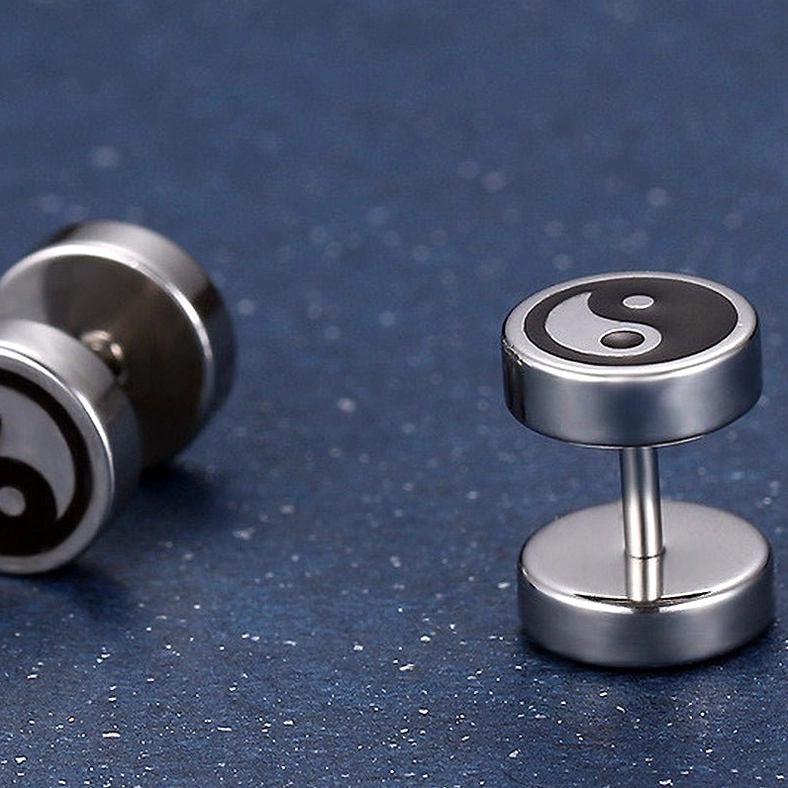 Yin yang stud earrings display from multiple angles, dumbbell-shaped stainless steel with Tai Chi symbol, dark blue sparkly background